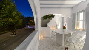 A modern outdoor dining area with white furniture and a white exterior wall. - Naxos Evilion (Naxos)