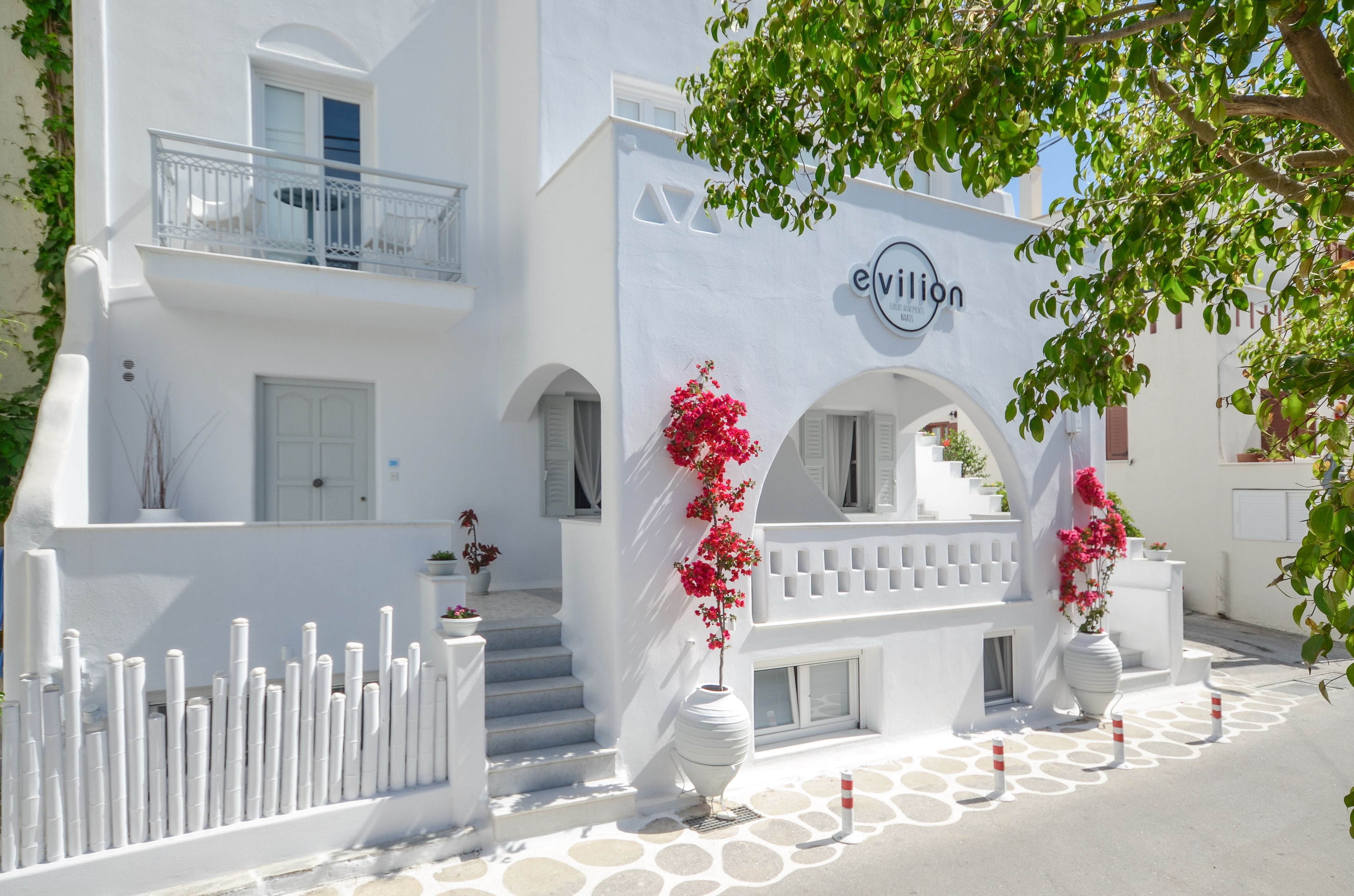 A white building with a balcony, a sign reading "evillion," and a white fence.