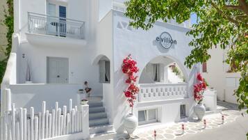 A white building with a balcony, a sign reading "evillion," and a white fence.