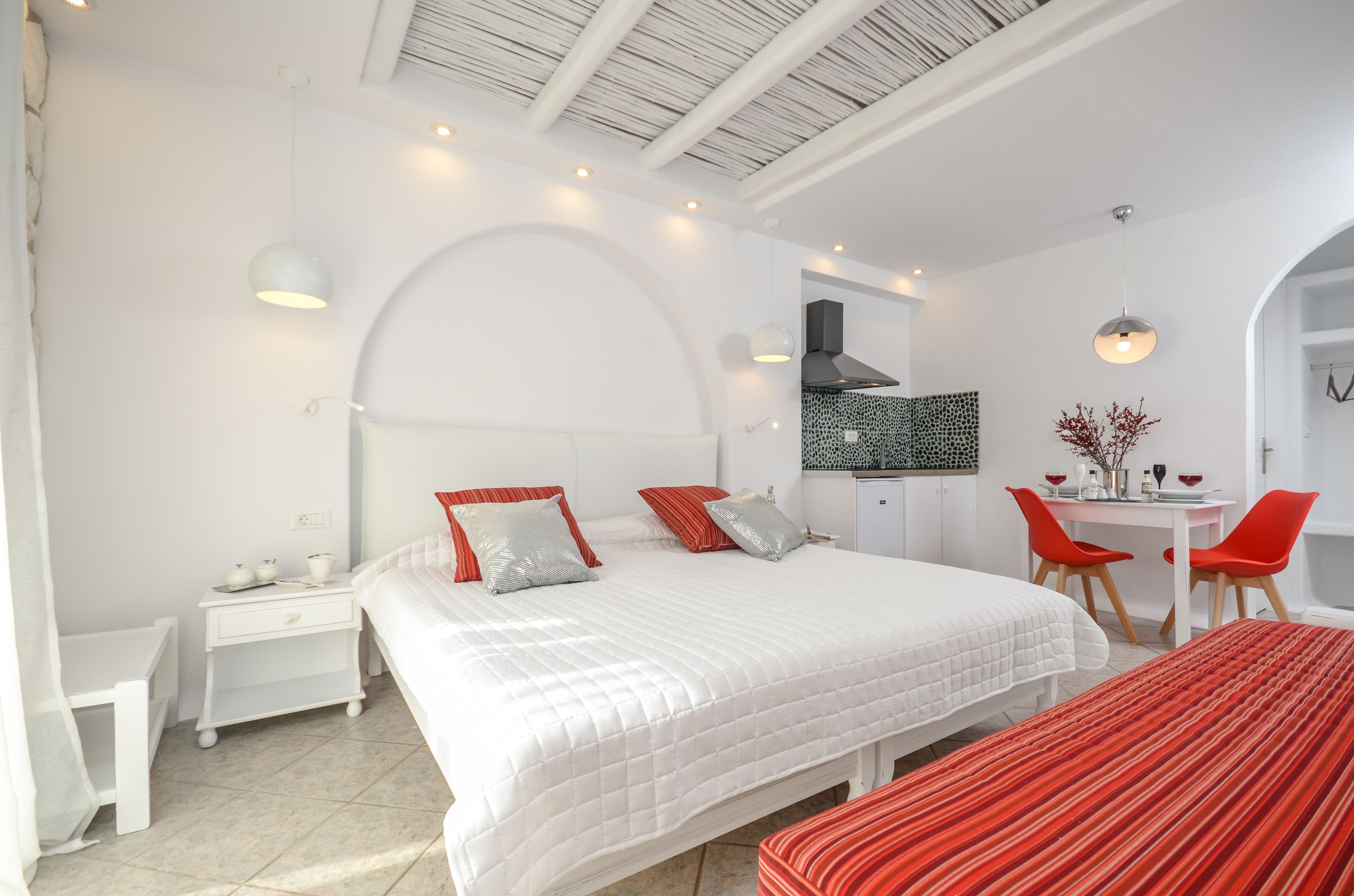 A modern hotel room with a large bed, a desk, and a dining area.