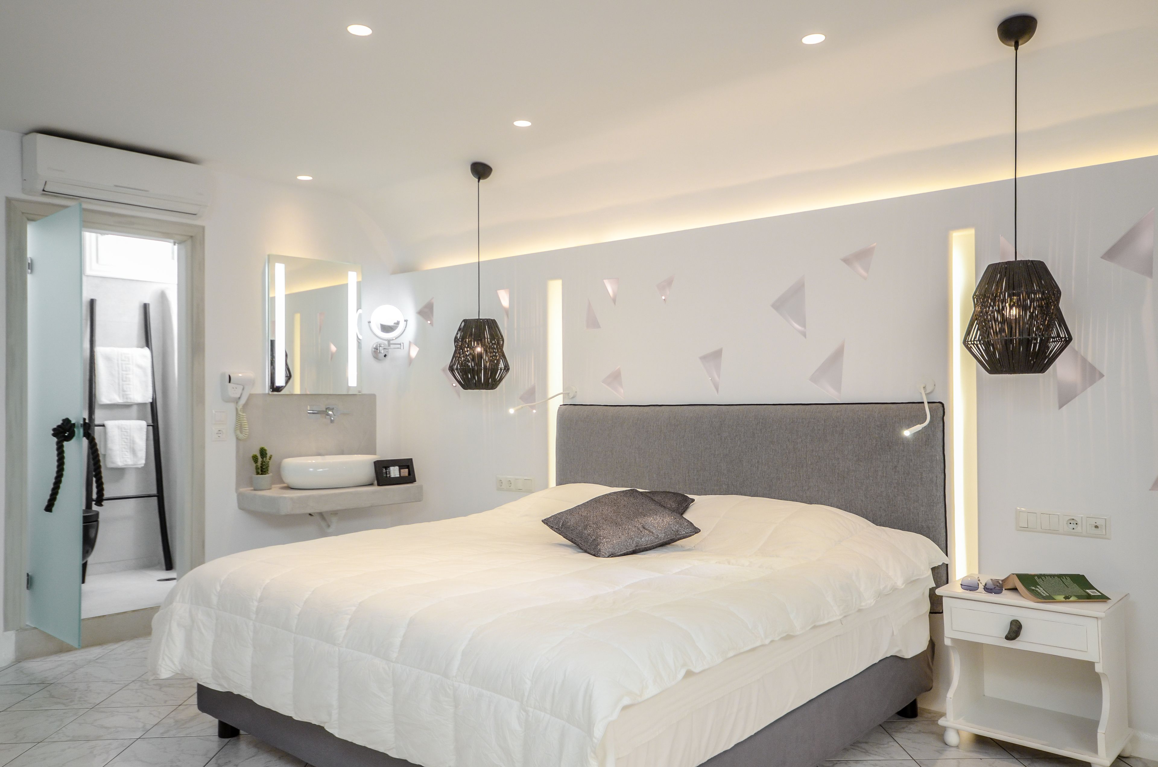 A modern bedroom with a large bed, bedside tables, a built-in shelf, and a hanging light fixture.