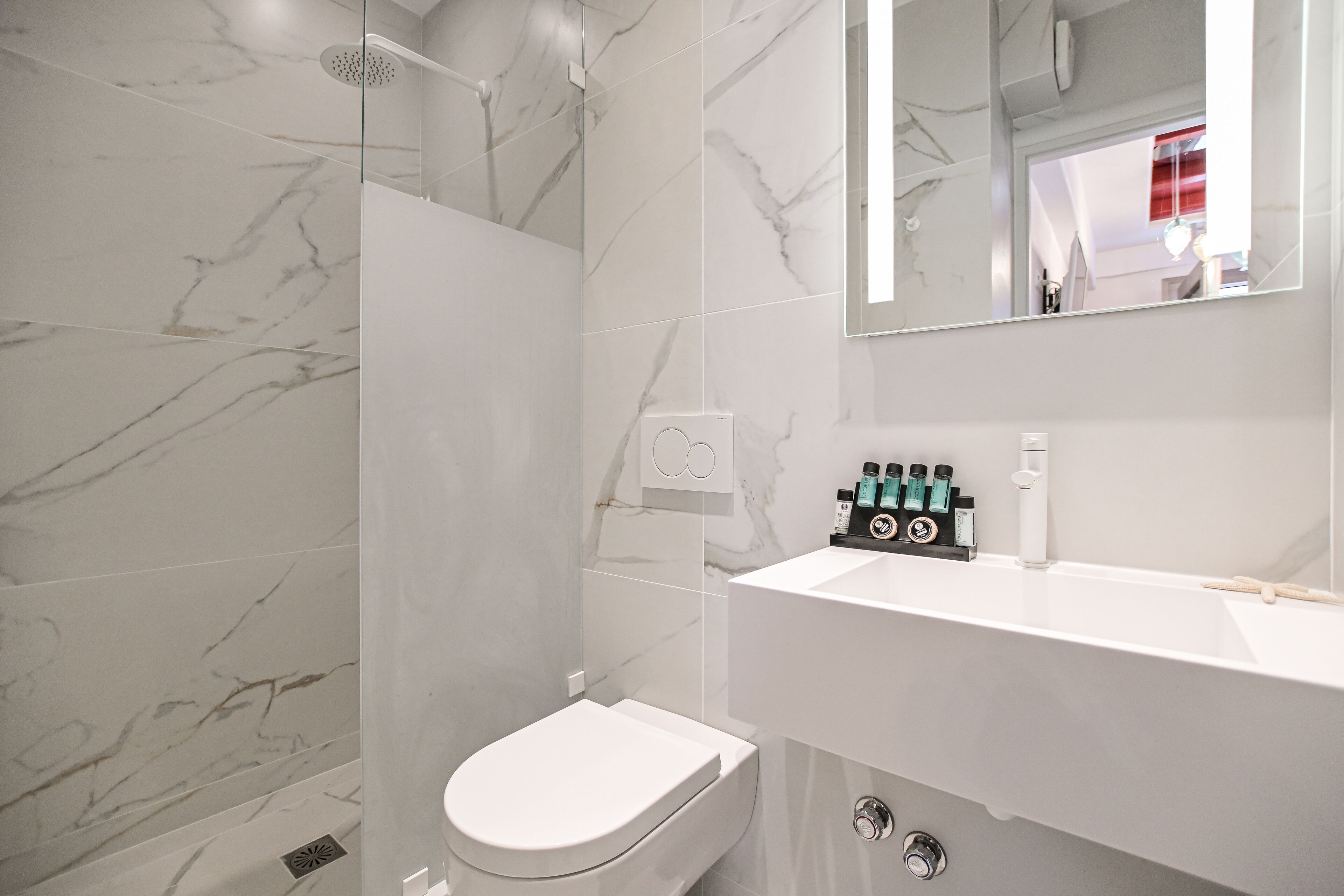 A modern bathroom with a white toilet, a shower, and a sink with toiletries.