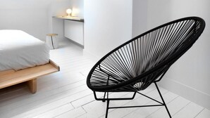 A modern bedroom with a bed, a black wireframe chair, a TV on the wall, and a skylight. - HAPPY Guesthouse (Brussels)