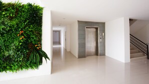 A modern interior with a green wall installation, a metallic elevator, and a staircase. - B2 Korat Boutique & Budget Hotel (Nakhon Ratchasima)