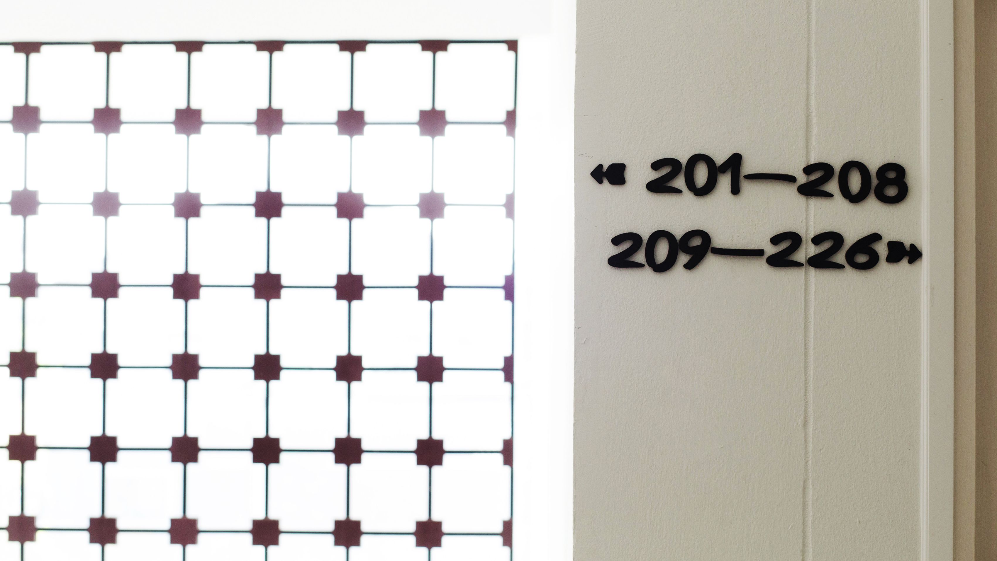 Ett rutmönster på en dörr och en vägg med rum nummer "201–208" och "209–226".