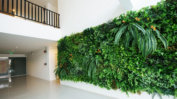 A modern interior with a large green wall of plants, a polished floor, and a metal railing on an upper level. - B2 Korat Boutique & Budget Hotel (Nakhon Ratchasima)