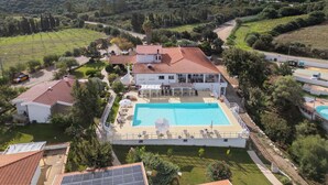 Une vaste villa dotée d’une piscine, entourée d’une végétation luxuriante et de montagnes.