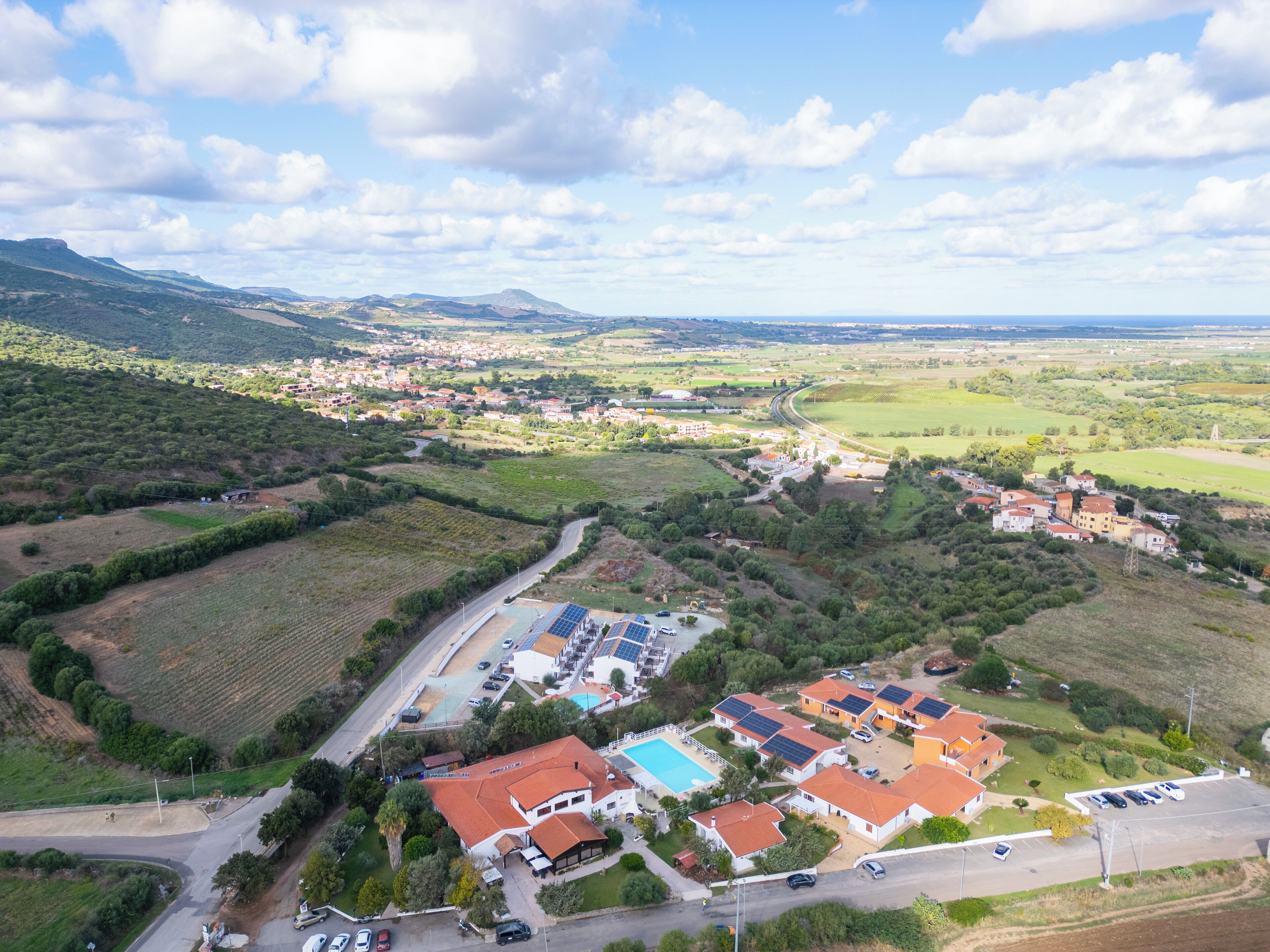 Vue aérienne d’un quartier résidentiel avec des maisons, une piscine et des panneaux solaires.