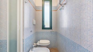 Un baño con inodoro, bidé y lavabo, con azulejos azules y blancos.