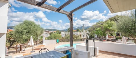 Un patio exterior con piscina, mobiliario y vistas del paisaje circundante.