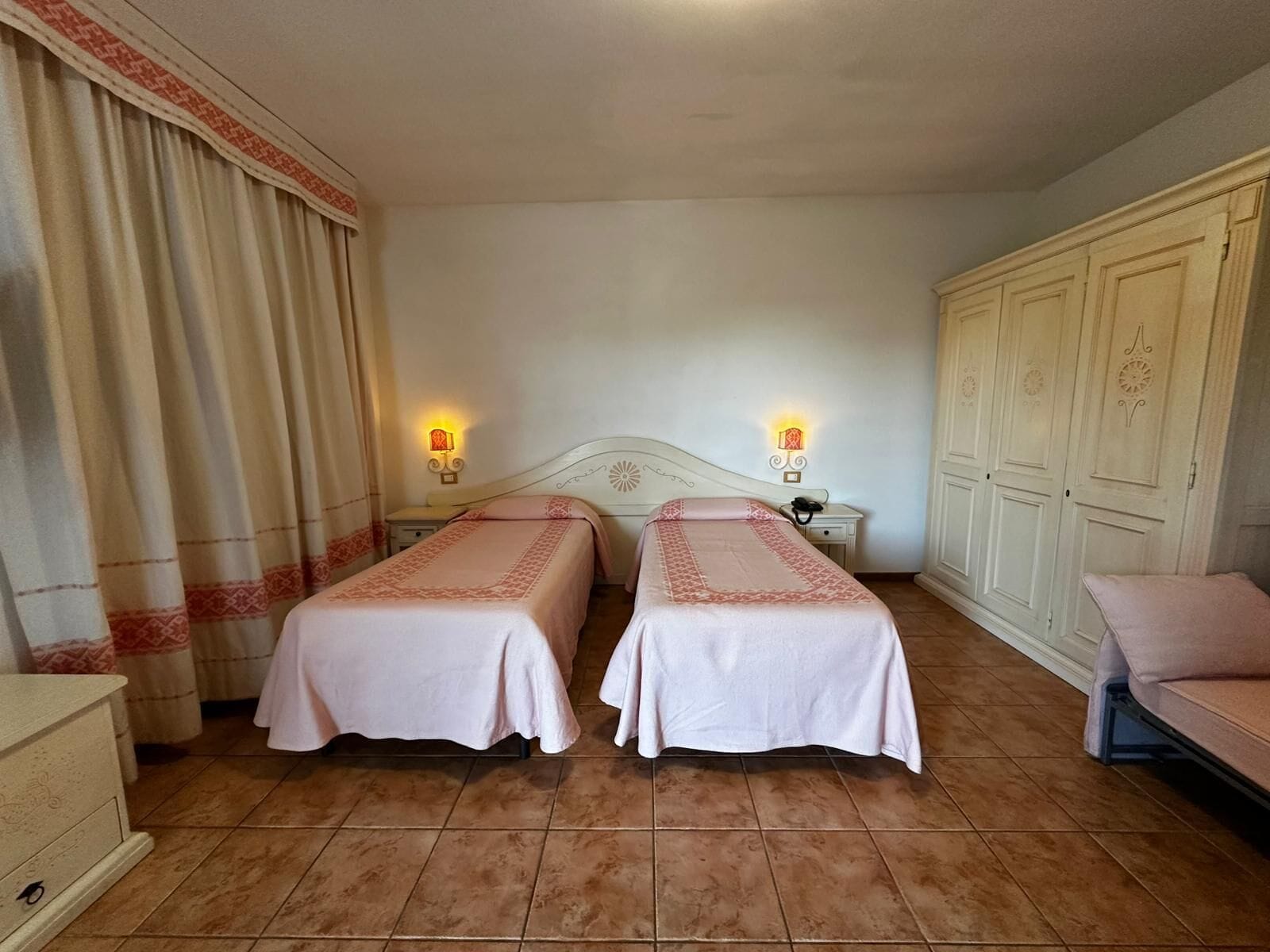 Una habitación de hotel con dos camas, una mesita de noche, un aparador y un armario.