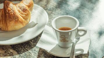 A croissant and a cup of coffee on a plate with a napkin, placed on a marble table.