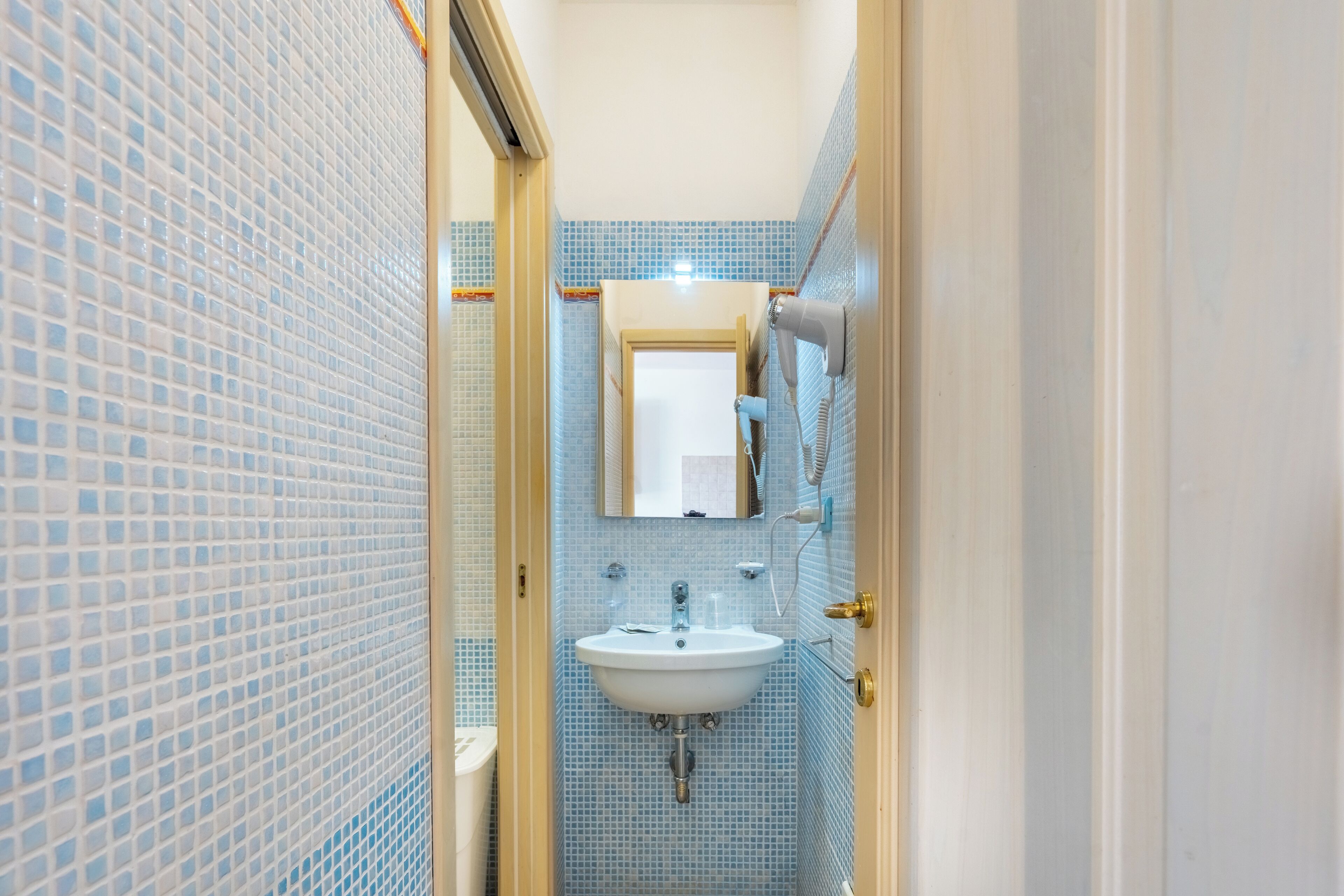 Un baño con lavamanos, espejo y perchero para toallas.