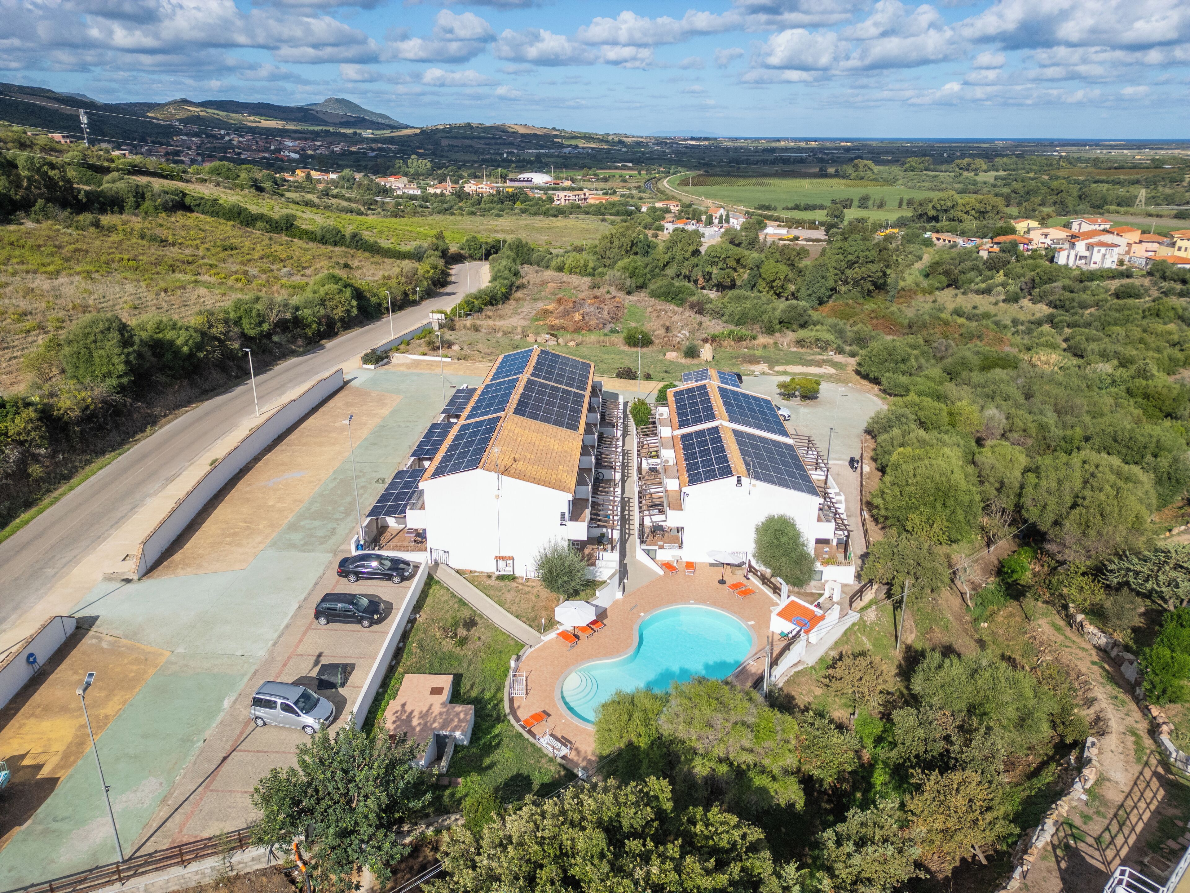 A residential property with solar panels, a swimming pool, and a view of the surrounding countryside.