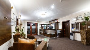 A hotel lobby with a reception desk, seating area, and a reception counter. - Grand Hotel Senica (Senica)