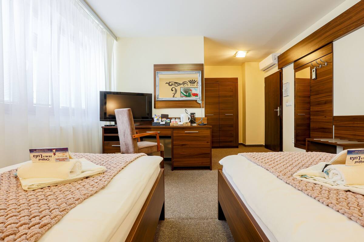 Una habitación de hotel con dos camas, un escritorio, una silla, un televisor y un armario.