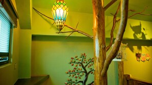 Una escalera con barandilla de madera, una escultura de árbol decorativa y un farol colgante.