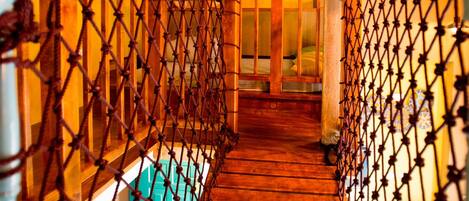 A wooden staircase with a netted railing, leading to a room with a wooden door and a small window.