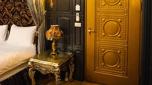 Una habitación con una cama, una mesa con una lámpara, un equipo de aire acondicionado y una puerta decorativa.