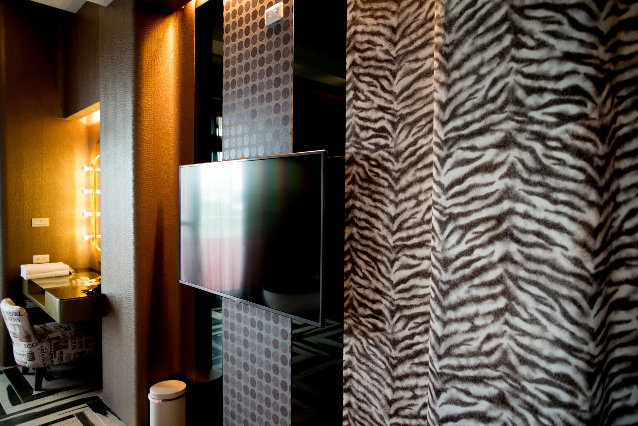 Une salle de bain moderne avec un grand miroir, un téléviseur à écran plat et un rideau de douche à motifs zébrés.