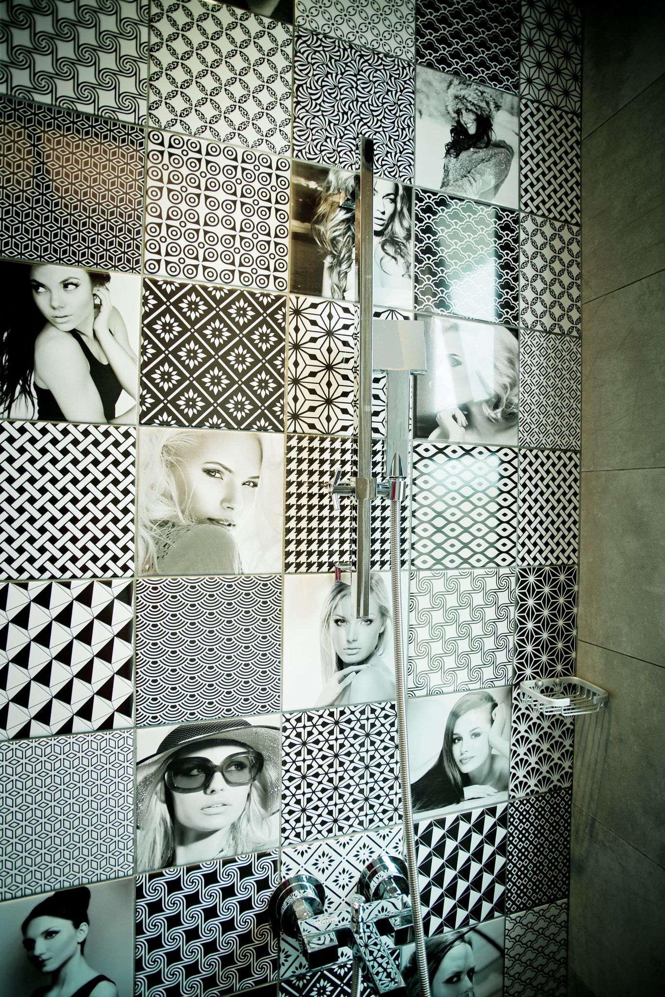 A bathroom with a tiled wall featuring various geometric patterns and photographs.