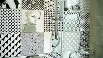 A bathroom with a tiled wall featuring various geometric patterns and photographs.