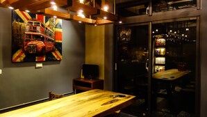 Un interior moderno con una mesa de comedor de madera, un cuadro grande de un autobús rojo de dos pisos y una pared de vidrio con vistas a la ciudad.