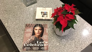 A magazine on a table with a coffee table, a small potted plant, and a larger potted plant with red flowers.