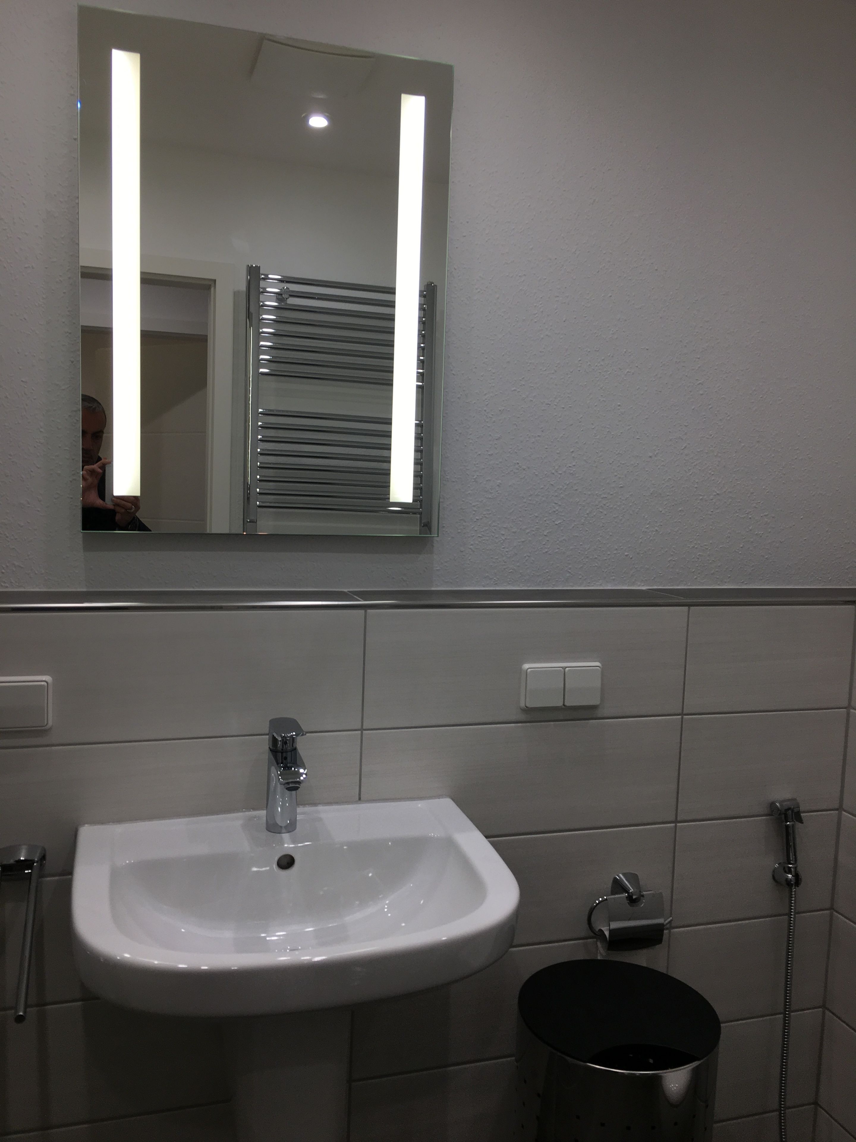 Ein Badezimmer mit einem weißen Waschbecken, einem Spiegel und einem Handtuchhalter.