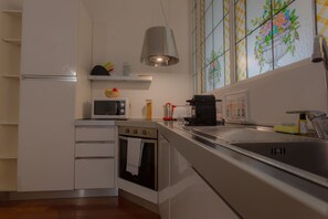 A modern kitchen with white cabinetry, a built-in oven, a microwave, and a stainless steel sink. - Italianway   - Dogana 3 (Milan)