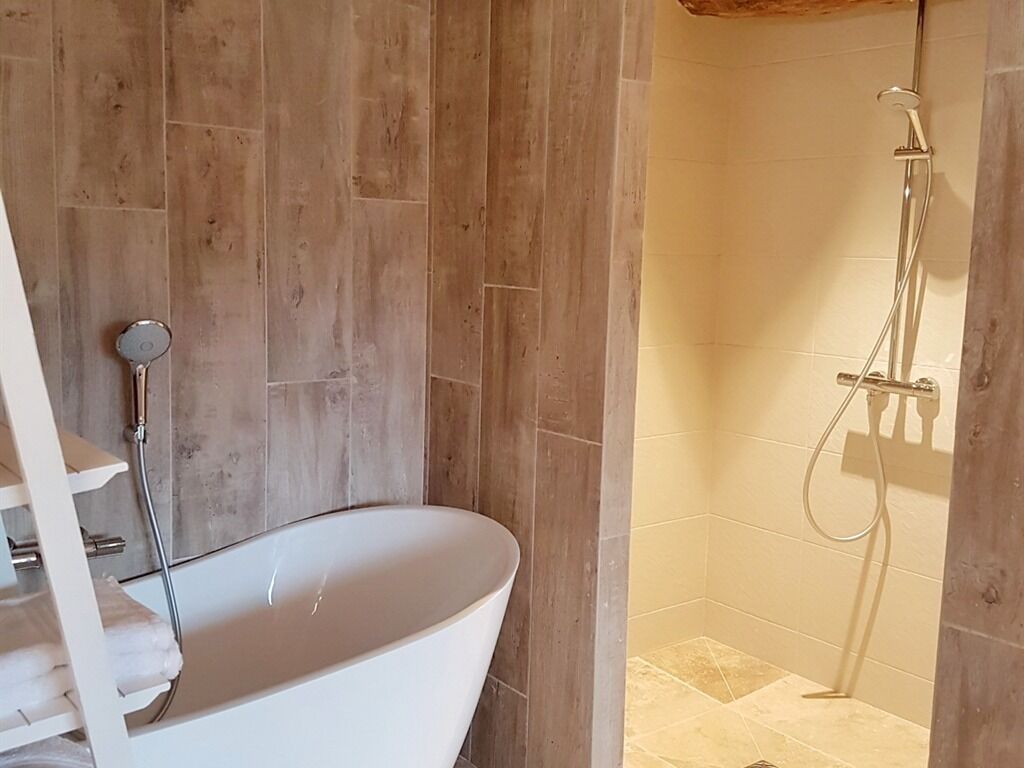 Un baño con bañera independiente, zona de ducha y suelo de madera.