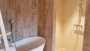 Un baño con bañera independiente, zona de ducha y suelo de madera.