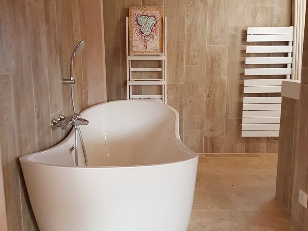 Une salle de bain moderne avec une baignoire sur pieds, une douche et un porte-serviettes.
