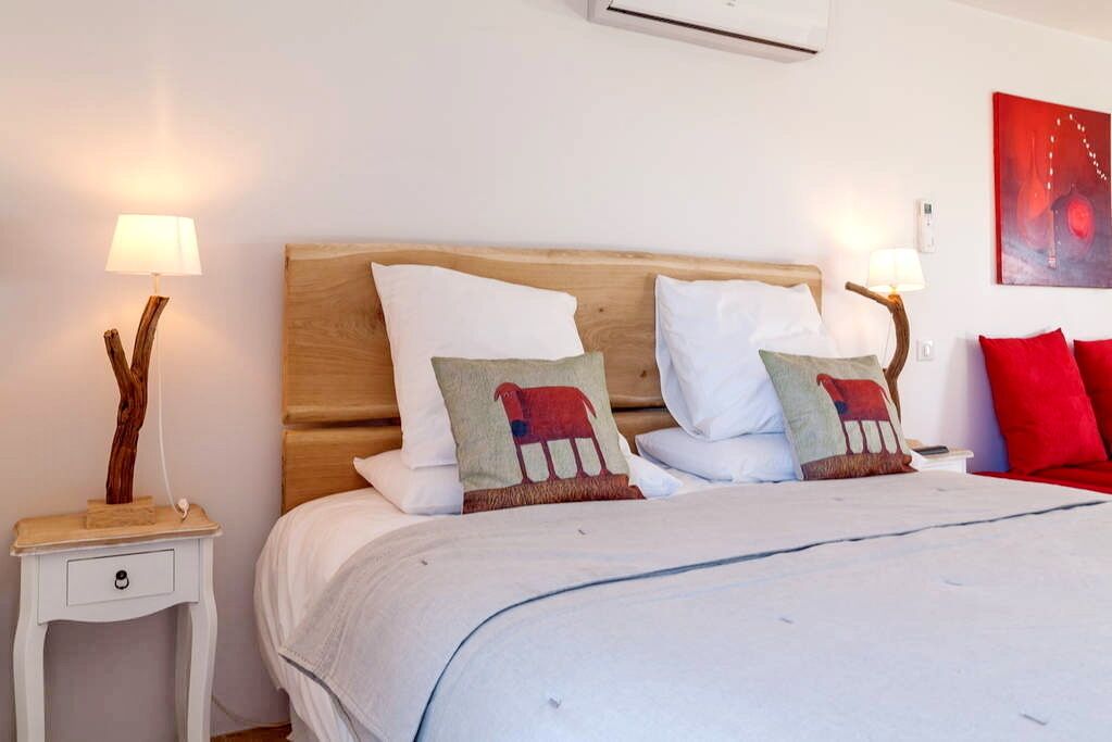 A neatly made bed with white bedding and decorative pillows, a wooden headboard, and a small bedside table with a lamp.