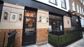 A building with a black entrance door, a sign reading "The House of Toby," and a small garden area with a black metal fence. - House of Toby (London)