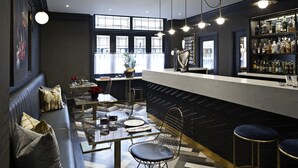 A modern bar area with a counter, seating, and a bar stocked with liquor bottles. - House of Toby (London)