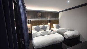 A hotel room with two beds, a headboard with a decorative panel, bedside lamps, and a small table. - House of Toby (London)