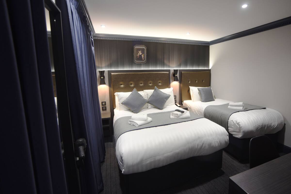 A hotel room with two beds, a headboard with a decorative panel, bedside lamps, and a small table.