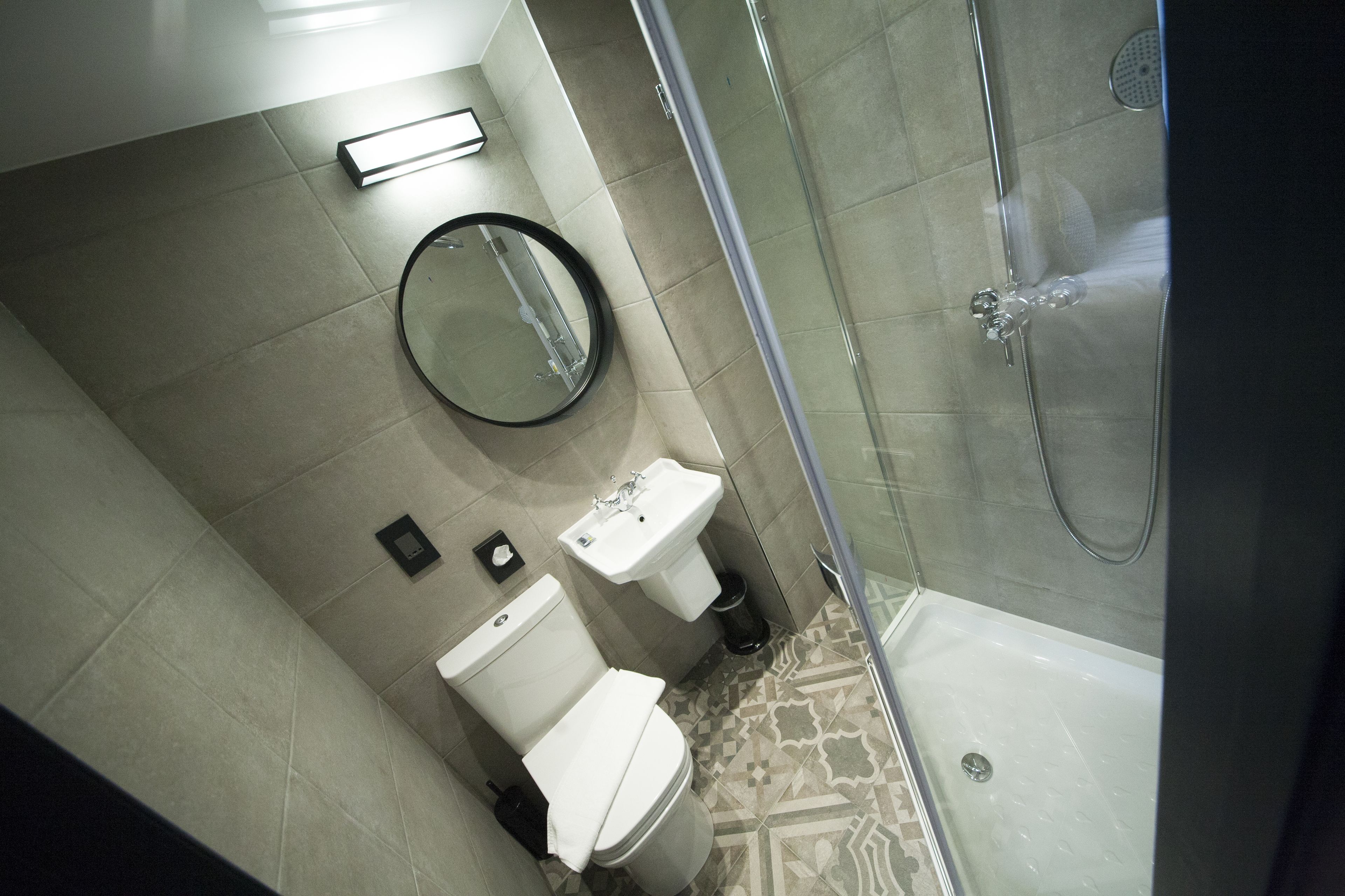 Ein Badezimmer mit Dusche, zwei Waschbecken, Toilette und Spiegel.