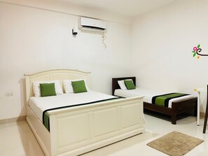 A bedroom with two beds, an air conditioning unit, a desk, and a small rug. - Seasons Villa (Inamaluwa)