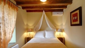 Een slaapkamer met een hemelbed, twee bedlampjes, een radiator en een ingelijst kunstwerk aan de muur.