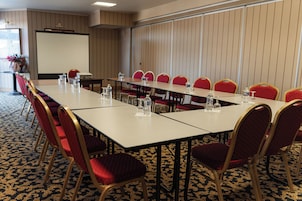 A conference room with a long table, red chairs, and water bottles.