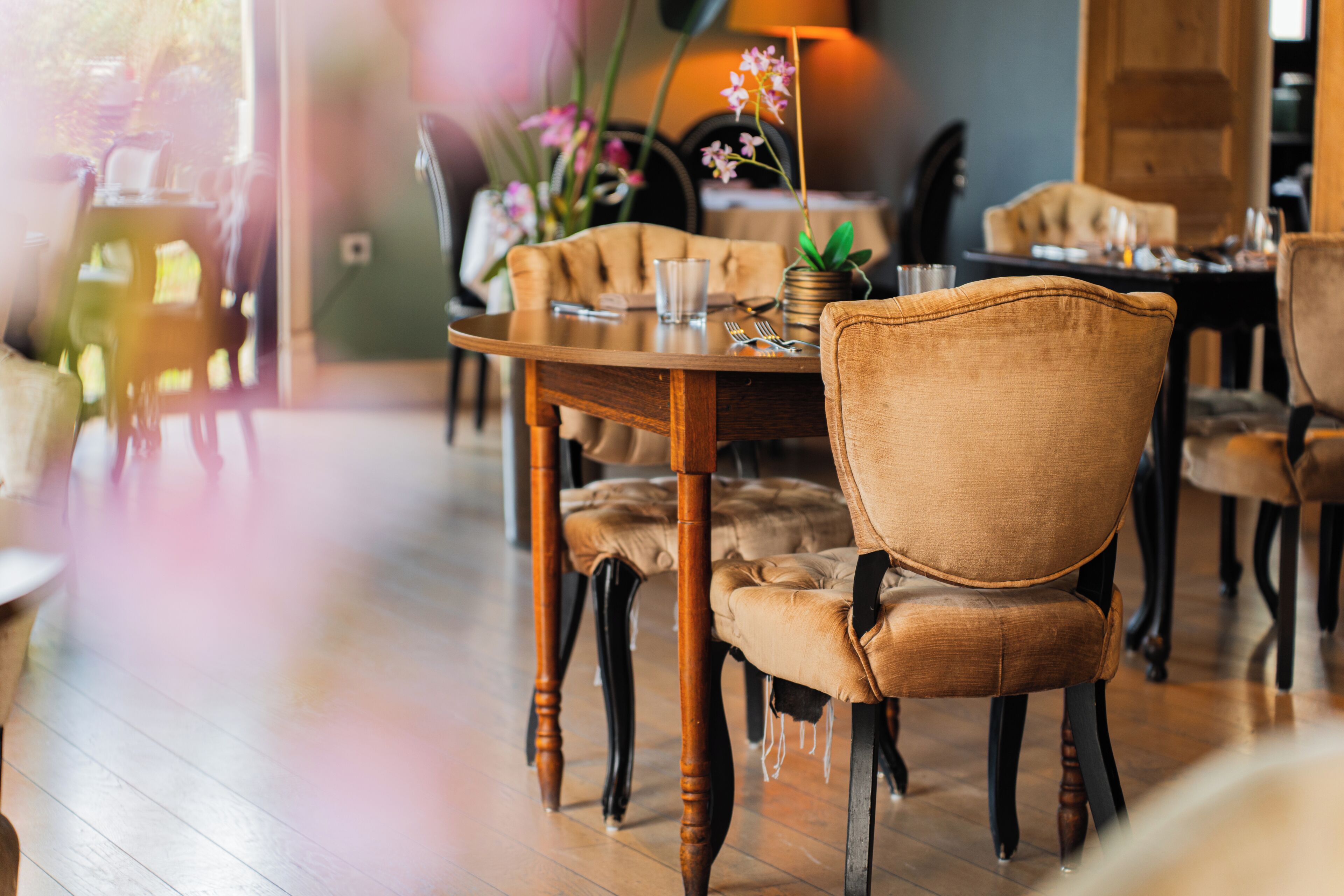 A dining area with wooden tables, cushioned chairs, and a vase with flowers.