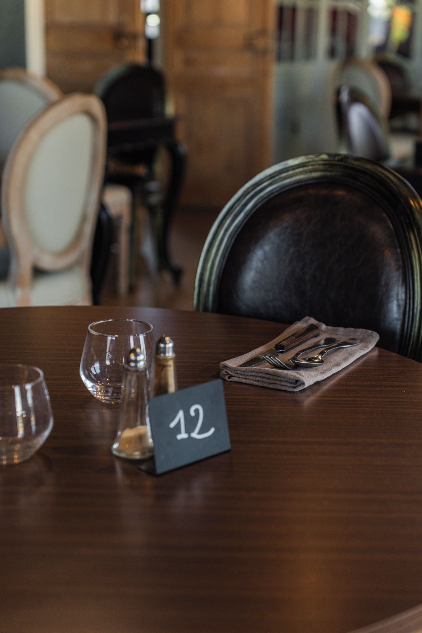 A dining table with a number sign, glasses, and cutlery.