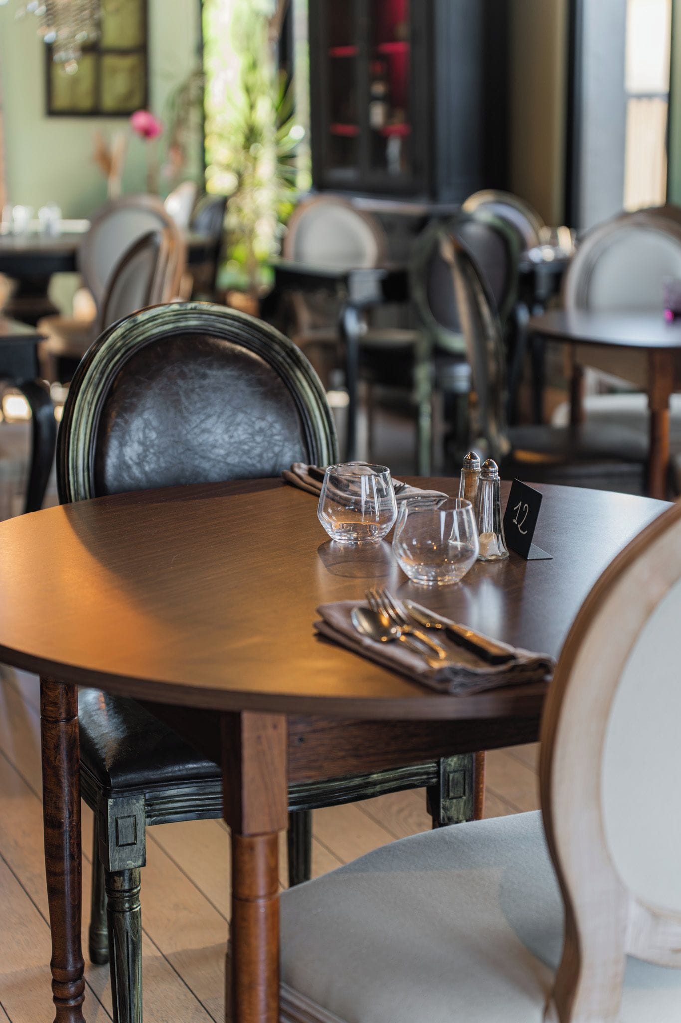 Una mesa de comedor con una placa, vasos y cubiertos.