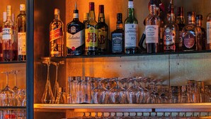 A bar area with shelves of liquor bottles and numerous wine glasses. - Hôtel Mercator (Vendome)