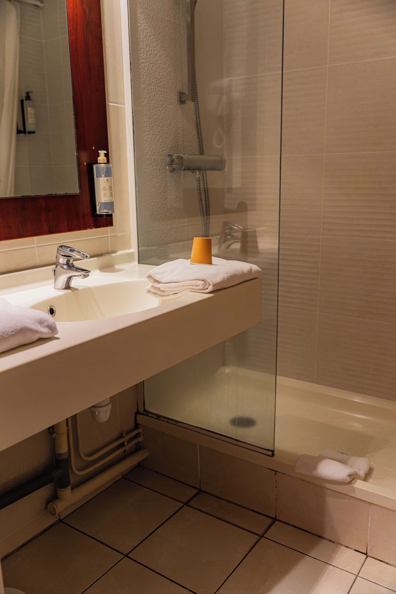 Une salle de bain avec un lavabo, un miroir et une douche.