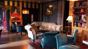 A cozy lounge area with a sofa, armchairs, a small table, and a bookshelf. - Hôtel Mercator (Vendome)