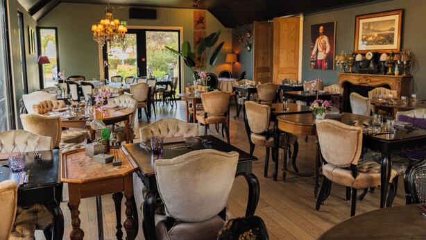 A dining area with multiple tables and chairs, a chandelier, and framed artwork on the walls. - Hôtel Mercator (Vendome)