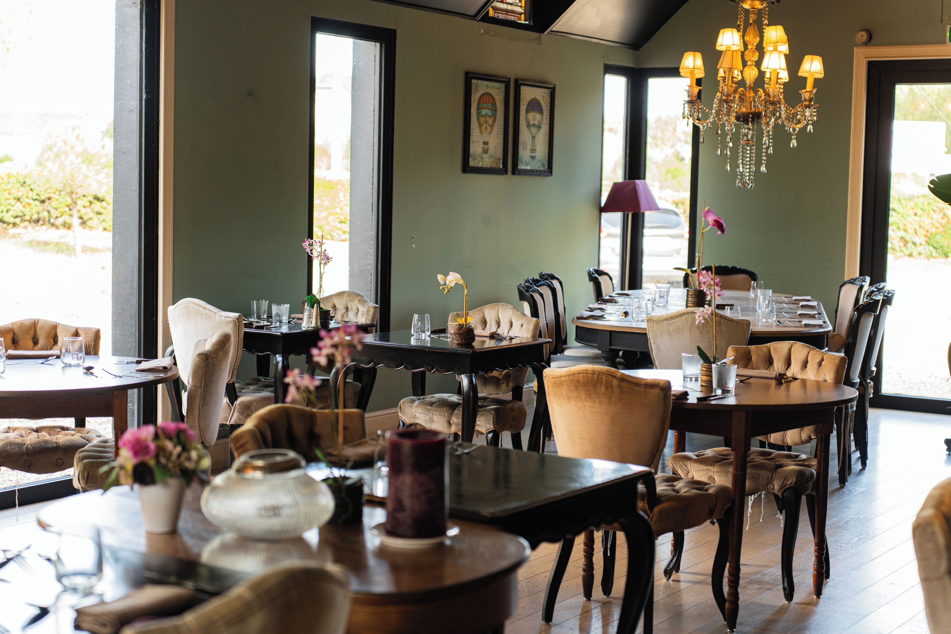 Un restaurant doté de plusieurs tables, de chaises et d’un lustre.